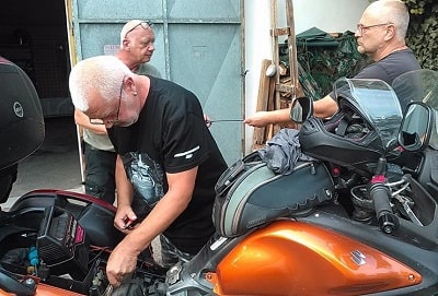 An old man try to push start a motorcycle that have dead battery. 